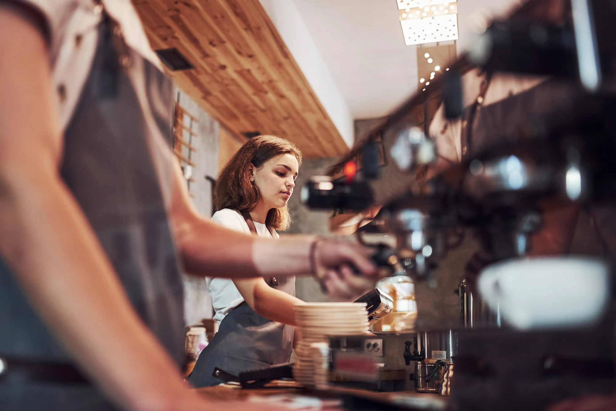 Blick entlang der Espressomaschine auf eine Mitarbeiterin.