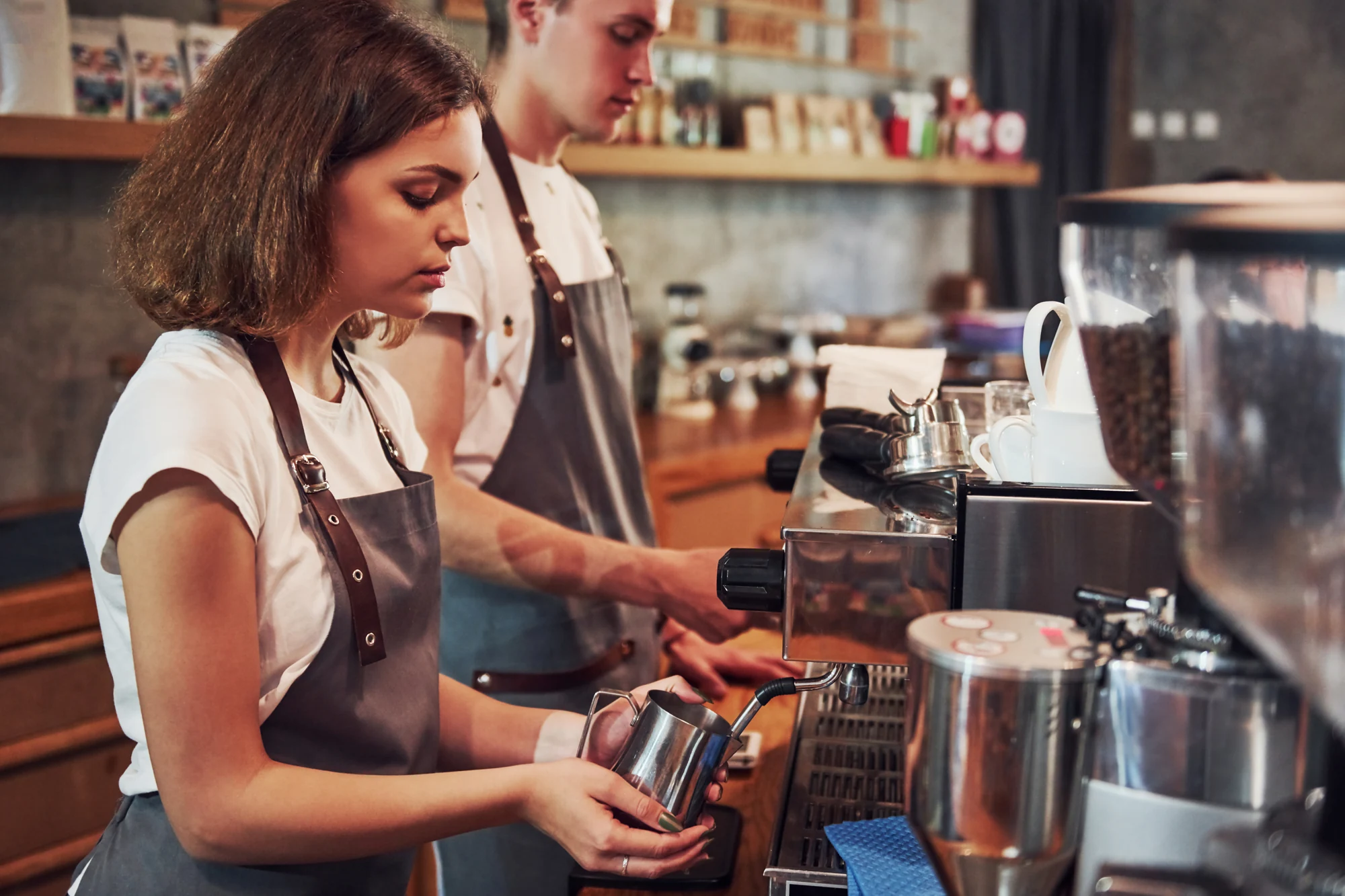 Zwei Menschen arbeiten an einer Espressomaschine im Café.